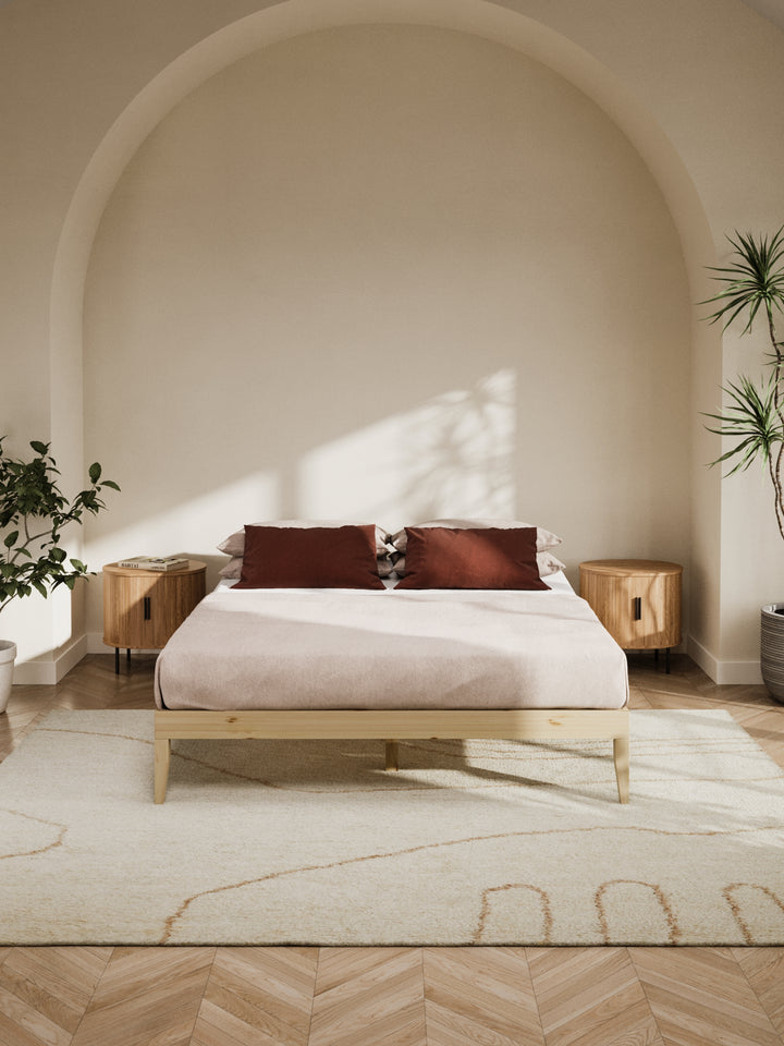 Contemporary bedroom featuring the Ventura Classic Wooden Bed Base in a clean, minimalist design. The natural light highlights the bed's sturdy construction and elegant finish, perfect for those looking to enhance their home with durable, stylish furniture. Paired with soft beige bedding and a lush view from the window, this bed base is ideal for modern décor enthusiasts.